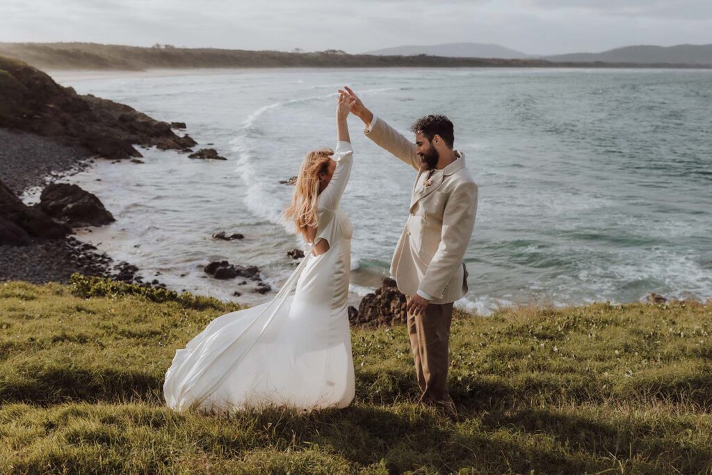Bride and groom dancing in front of a beautiful ocean background