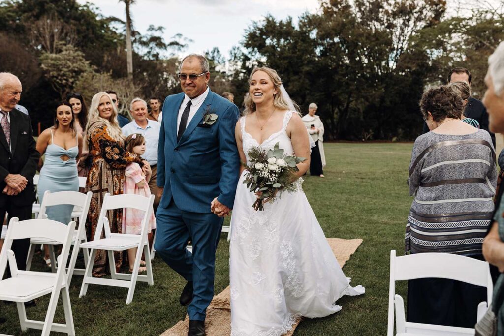Bride and her dad walking down the aisle with big smiles on their face